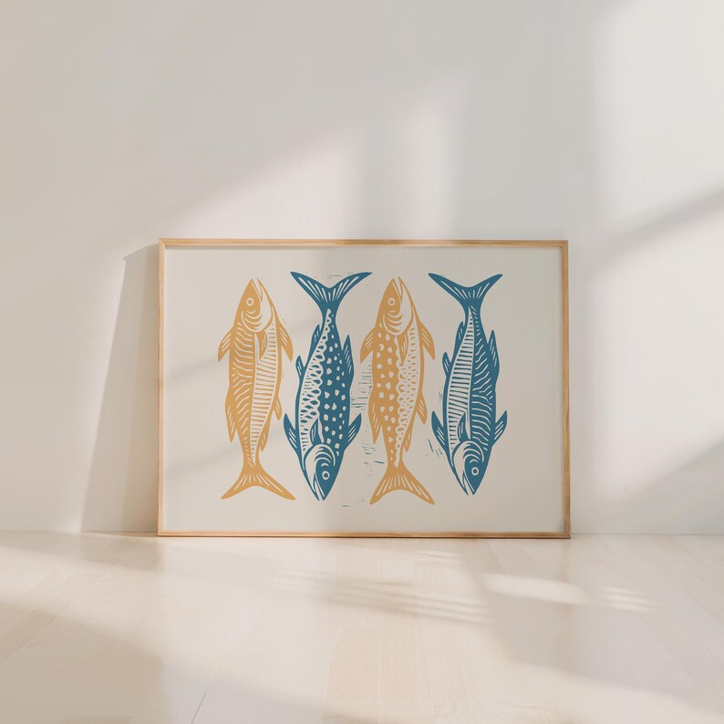 May include: A framed art print featuring four stylized fish in a row. Two fish are a golden yellow color, and two are a deep blue. The fish are arranged on a cream-colored background, with a natural wood frame.