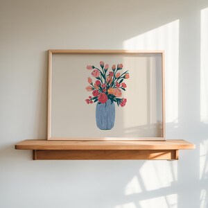May include: A framed print of a floral arrangement in a blue vase. The flowers are pink, orange, and yellow. The print is on a light beige background.
