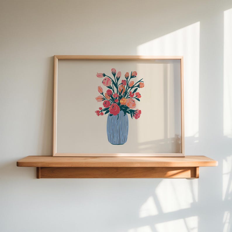 May include: A framed print of a floral arrangement in a blue vase. The flowers are pink, orange, and yellow. The print is on a light beige background.