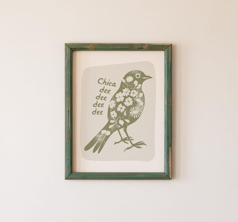 May include: A framed print of a green bird with white flowers on its body. The bird is perched on a branch and the text "Chica dee dee dee dee" is written below it.