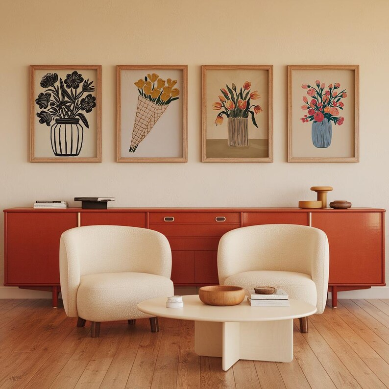 May include: Four framed prints of floral arrangements in different styles. The prints are hung on a wall above a red cabinet with two white chairs and a coffee table.