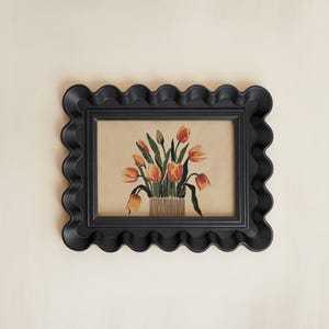 Peut inclure: Un cadre noir à coquille avec une peinture de tulipes orange dans un vase. La peinture est sur un fond crème.
