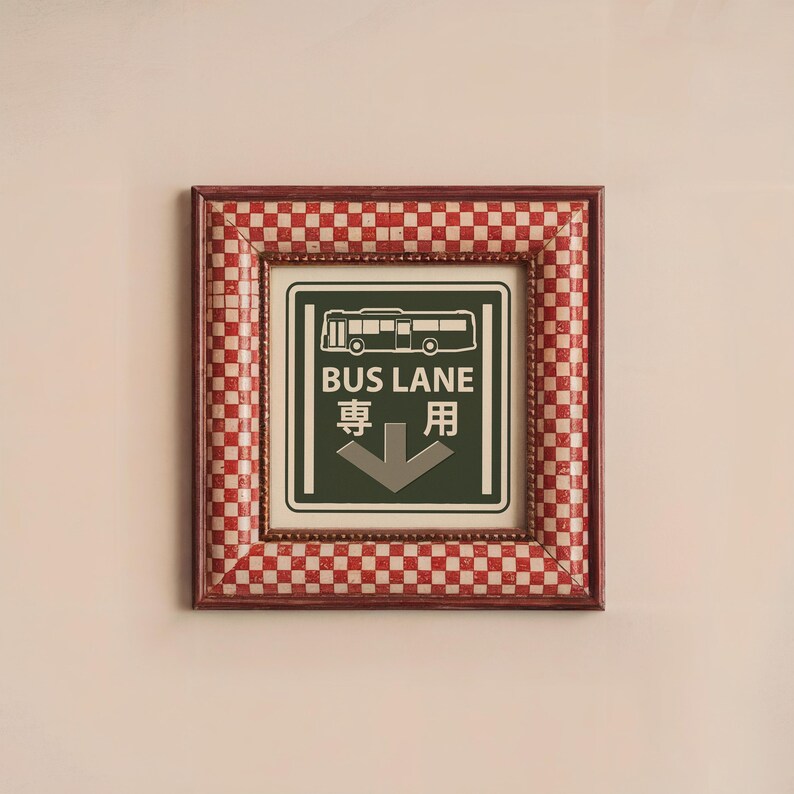 May include: A red and white checkered frame with a green sign that says "BUS LANE" in white letters and "専用" in black letters. The sign also has a white silhouette of a bus and a white arrow pointing down.