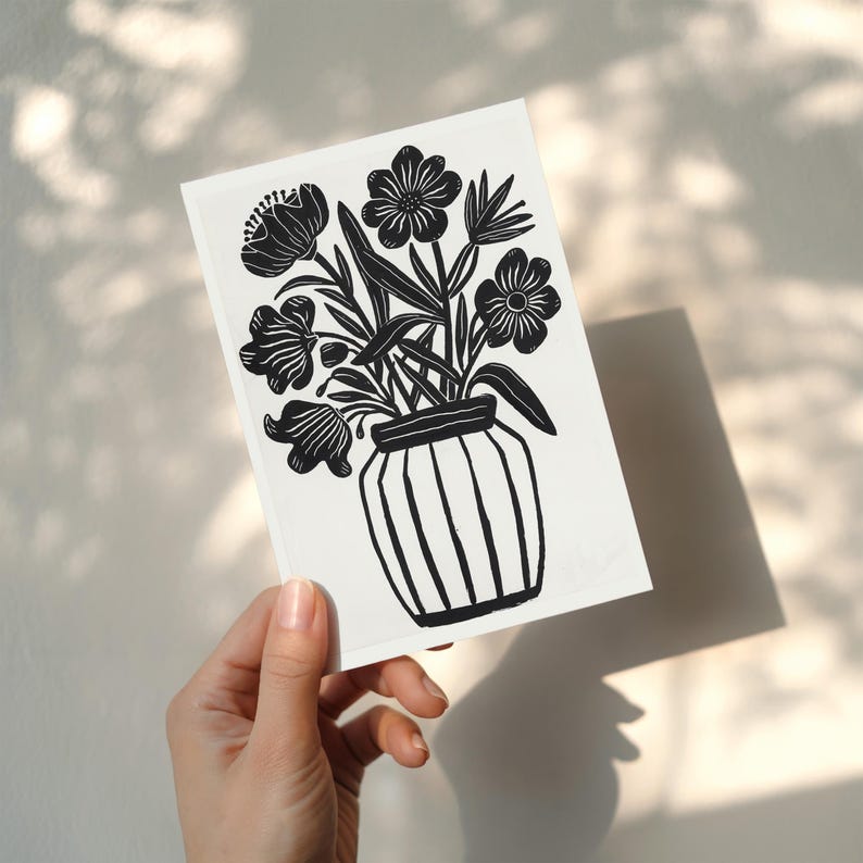 Puede incluir: Impresi&oacute;n art&iacute;stica en blanco y negro que representa un jarr&oacute;n con flores estilizadas. El jarr&oacute;n tiene rayas verticales. La impresi&oacute;n se sostiene en una mano, con sombras en el fondo.