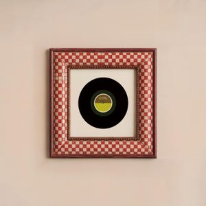 May include: A framed vinyl record with a black and green label. The label has the text "It's Time" and "Patty Time" on it. The frame is red and white checkered.