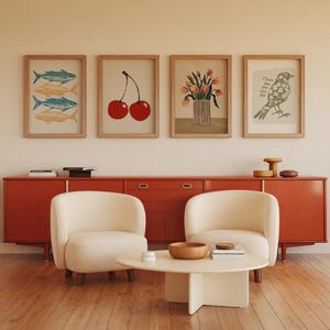 May include: A living room interior with a red cabinet, two white armchairs, and a coffee table. The wall above the cabinet is decorated with five framed prints, including a print of cherries, a print of fish, a print of flowers, and a print of a bird.