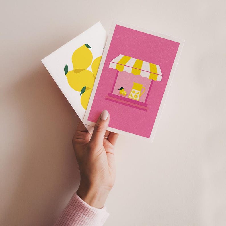 K&ouml;nnte beinhalten: Zwei Gru&szlig;karten mit einem Limonaden-Motiv. Eine Karte zeigt einen rosa Hintergrund mit einem gelben Limonadenstand und einem Krug mit Limonade. Die andere Karte zeigt einen wei&szlig;en Hintergrund mit einer Gruppe gelber Zitronen.