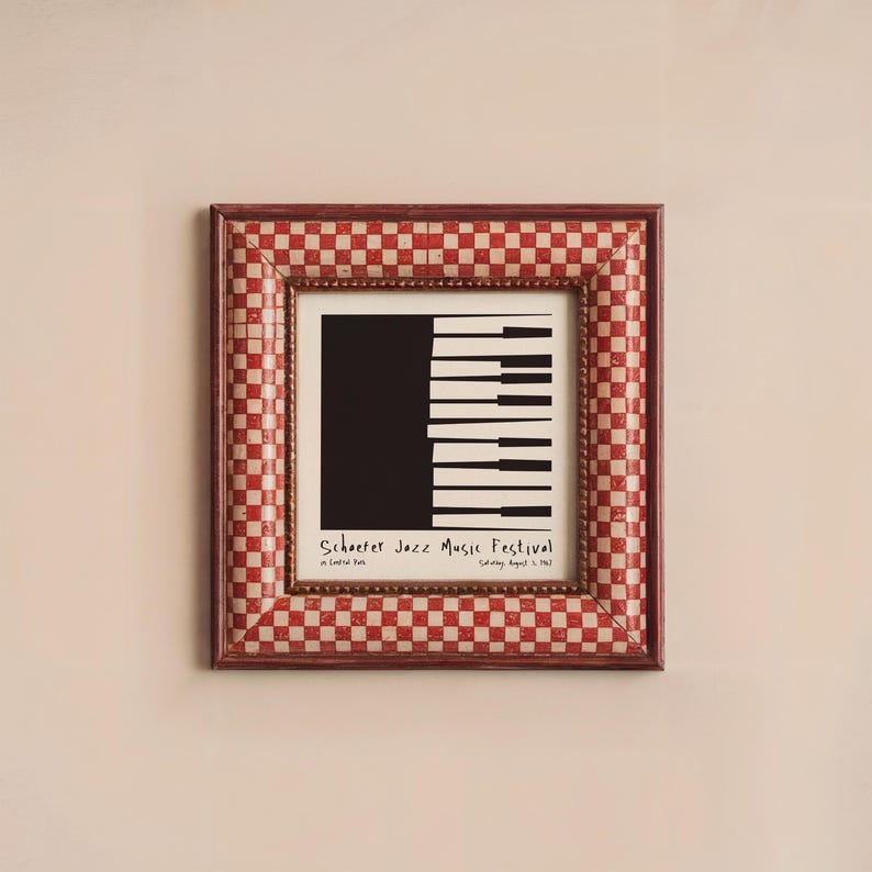 May include: A framed print with a red and white checkered border. The print features a black and white illustration of a piano keyboard with the text "Schroeder Jazz Music Festival" at the bottom.
