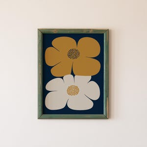 May include: A framed print featuring two large stylized flowers. The top flower is mustard yellow and the bottom flower is white with a light gray center. The background is a dark blue.