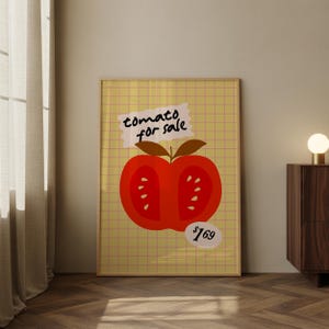 May include: A framed art print featuring a stylized red tomato illustration. The tomato is cut in half, revealing seeds, and is set against a yellow grid background. Text above reads "tomato for sale".