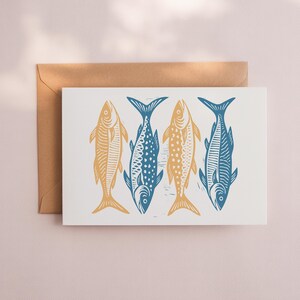 May include: A greeting card featuring four stylized fish illustrations. Two fish are yellow, and two are blue, all against a white background. The card is accompanied by a brown envelope, perfect for sending a nautical-themed message.
