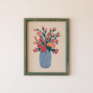 May include: A framed print of a colorful floral arrangement in a blue vase. The flowers are pink, orange, and red, and the vase has a textured pattern.