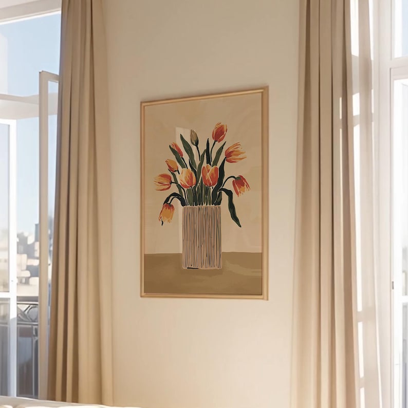 May include: A framed art print featuring a vase of orange and yellow tulips. The vase has vertical lines and sits on a tan background. The artwork is in a gold frame and hangs on a cream-colored wall.