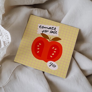 May include: A square card with a yellow grid pattern features a stylized illustration of a halved red tomato with brown leaves. The text "tomato for sale" is above the tomato, and a price tag reads "£169".