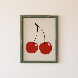 Puede incluir: Una pintura enmarcada de dos cerezas rojas con tallos, sobre un fondo blanco.