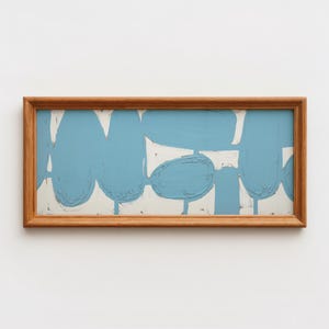 May include: Abstract art piece in a rectangular wooden frame. The artwork features light blue shapes on a white background. The frame is made of natural-toned wood, adding a warm contrast to the cool colors of the painting.