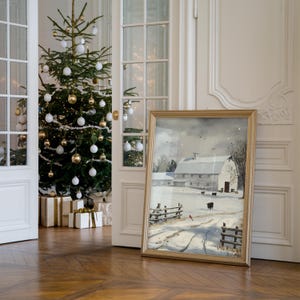 May include: A framed winter scene painting of a white barn with a snow-covered field and a fence. The painting is in a gold frame and is hanging on a white wall. A Christmas tree with white and gold ornaments is in the foreground.