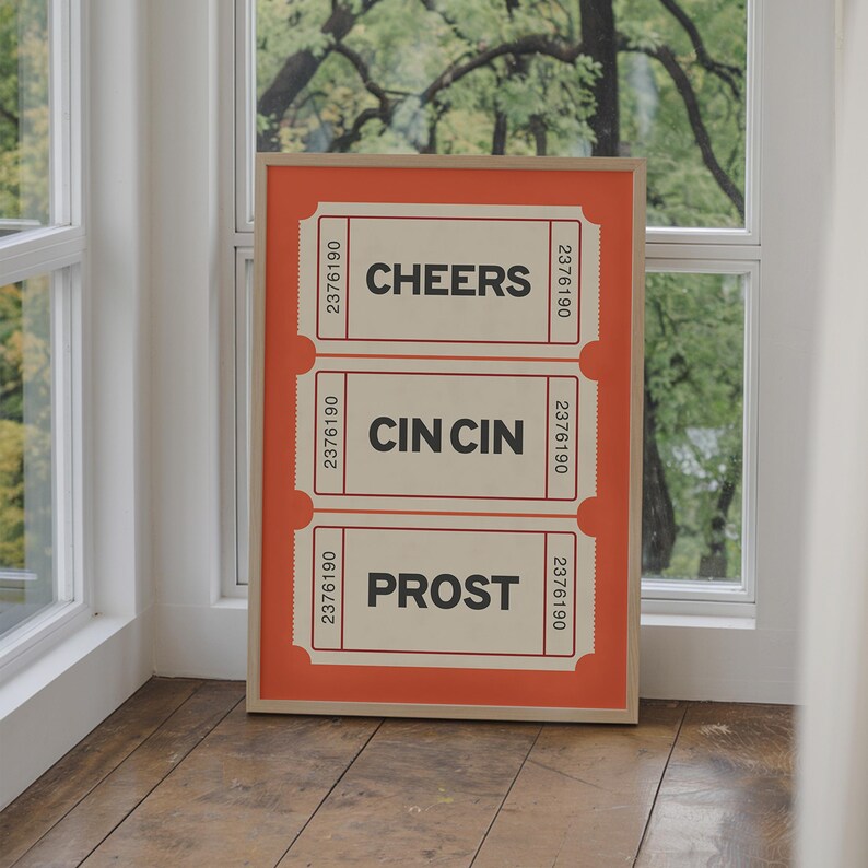 May include: A framed print with an orange background and three white ticket-shaped designs. Each ticket has a black number "2376190" on the left and right sides. The tickets read "CHEERS", "CIN CIN", and "PROST" in black text.