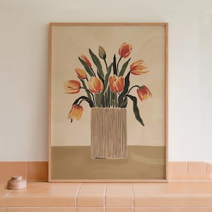 May include: A framed print of a still life featuring a bouquet of orange and yellow tulips in a striped vase. The background is a light beige color.