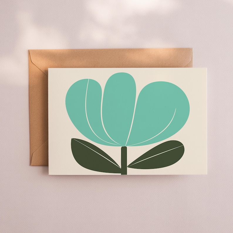 May include: A greeting card with a teal flower design and dark green leaves. The flower is centered on a cream-colored background. A brown envelope is behind the card. The design is simple and modern.
