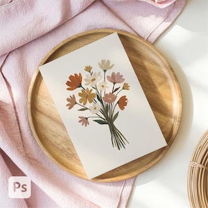 Peut inclure: Une impression d'art florale représentant un bouquet de fleurs aux tons orange, jaune, rose et blanc. L'œuvre est présentée sur un plateau en bois, sur fond de tissu rose. Le bouquet est lié avec des tiges vertes.