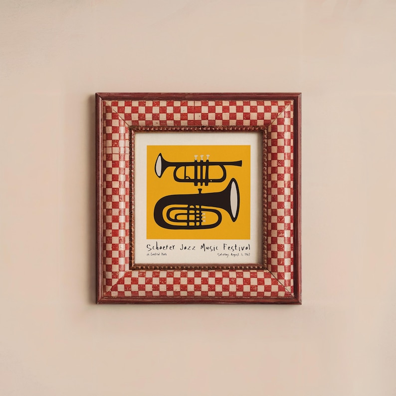 May include: A framed print of a black and white illustration of a trumpet and a trombone on a yellow background. The text "Schooner Jazz Music Festival" is printed below the instruments.