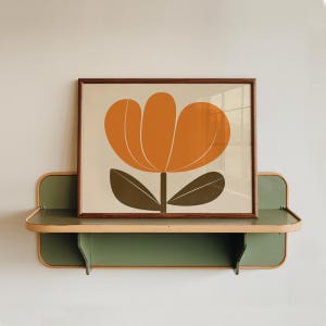 K&ouml;nnte beinhalten: Ein gerahmter Druck einer stilisierten orangefarbenen Blume mit gr&uuml;nen Bl&auml;ttern auf einem Holzregal. Das Regal ist gr&uuml;n mit einer hellbraunen Verkleidung.