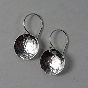 May include: A pair of silver hammered disc earrings with a simple hook closure.
