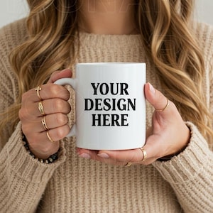 May include: A white ceramic mug with a black handle. The mug has the text "YOUR DESIGN HERE" printed on the front.