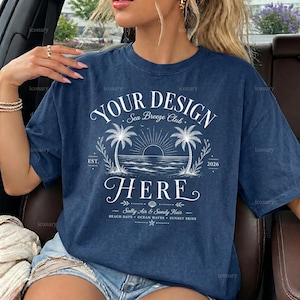 Pode incluir: Uma t-shirt azul-marinho de manga curta com uma estampa gráfica branca de palmeiras, um sol e ondas do mar. O texto diz: YOUR DESIGN HERE, Sea Breeze Club, EST. 2026, Salty Air & Sandy Hair, BEACH DAYS, OCEAN WAVES, SUNSET SKIES.