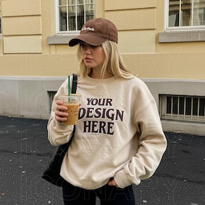 Może przedstawiać: Beżowa bluza z nadrukiem "YOUR DESIGN HERE" z przodu. Modelka nosi brązową czapkę z daszkiem z napisem "La Paris".