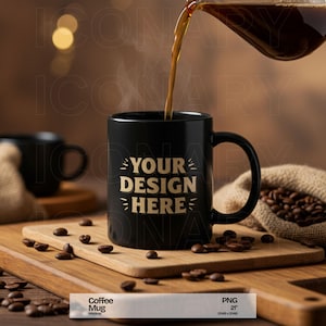 Może przedstawiać: Czarny kubek do kawy z złotym napisem "YOUR DESIGN HERE" na drewnianej powierzchni, wokół której rozrzucone są ziarna kawy. Kawa jest nalewana do kubka z szklanej karafki.