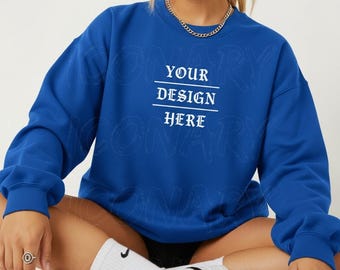 May include: A royal blue sweatshirt with the text "YOUR DESIGN HERE" in white. The sweatshirt has a crew neck and long sleeves. The image also shows a person wearing the sweatshirt.