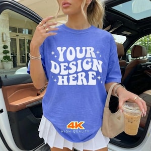 May include: A blue t-shirt with the text "YOUR DESIGN HERE" in white, with star accents. The shirt also has the text "4K HIGH QUALITY" at the bottom. The shirt is paired with a white pleated skirt.