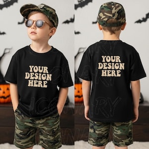 May include: A child wearing a black t-shirt and camouflage shorts. The front of the shirt has the text "YOUR DESIGN HERE" in a retro font. The child is also wearing a camouflage baseball cap and sunglasses. The back of the shirt also has the same text.