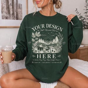 Può includere: Una felpa girocollo verde scuro con una stampa grafica bianca di un paesaggio boschivo con zucche, fogliame e il testo "YOUR DESIGN HERE", "Fall Harvest Club", "EST. 2026", "Golden Days, Cozy Ways, Grateful Hearts, Crisp Air, Cozy Nights, Autumn Soul."