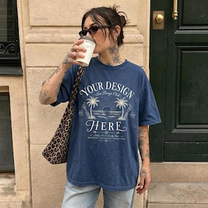 Pode incluir: Uma t-shirt de manga curta azul-marinho com uma estampa gráfica branca que diz YOUR DESIGN HERE, Sea Breeze Club, EST. 2020 e Beach Days Ocean Waves Sunset Skies. A t-shirt tem gola redonda e um corte largo e descontraído.
