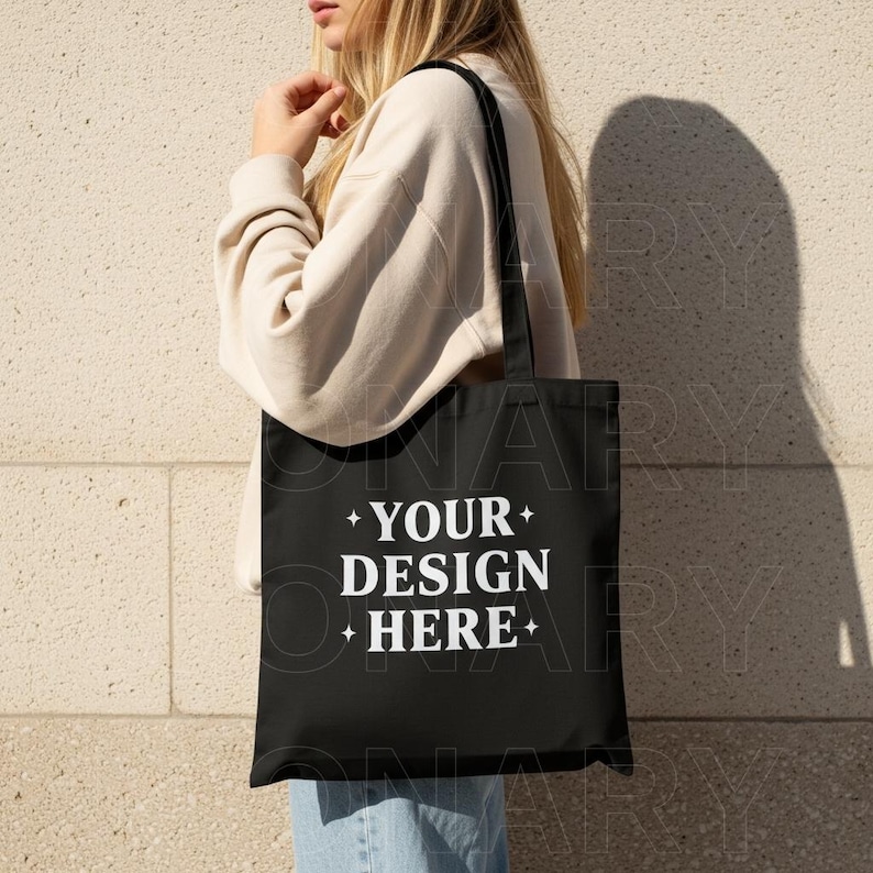 May include: A black tote bag with white text that reads "YOUR DESIGN HERE".
