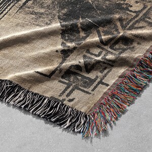 Pu&ograve; includere: Una coperta in tessuto intrecciato con un design astratto in bianco e nero e frange multicolori. La coperta &egrave; realizzata in un tessuto morbido e testurizzato.