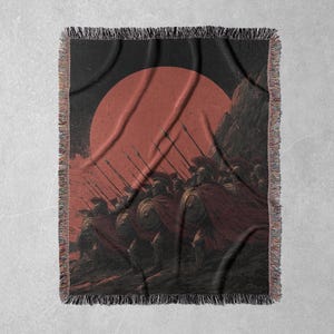 May include: Woven throw blanket featuring a historical illustration of a line of soldiers with spears, shields, and red capes, set against a red sun and dark background. The blanket has a fringed edge.