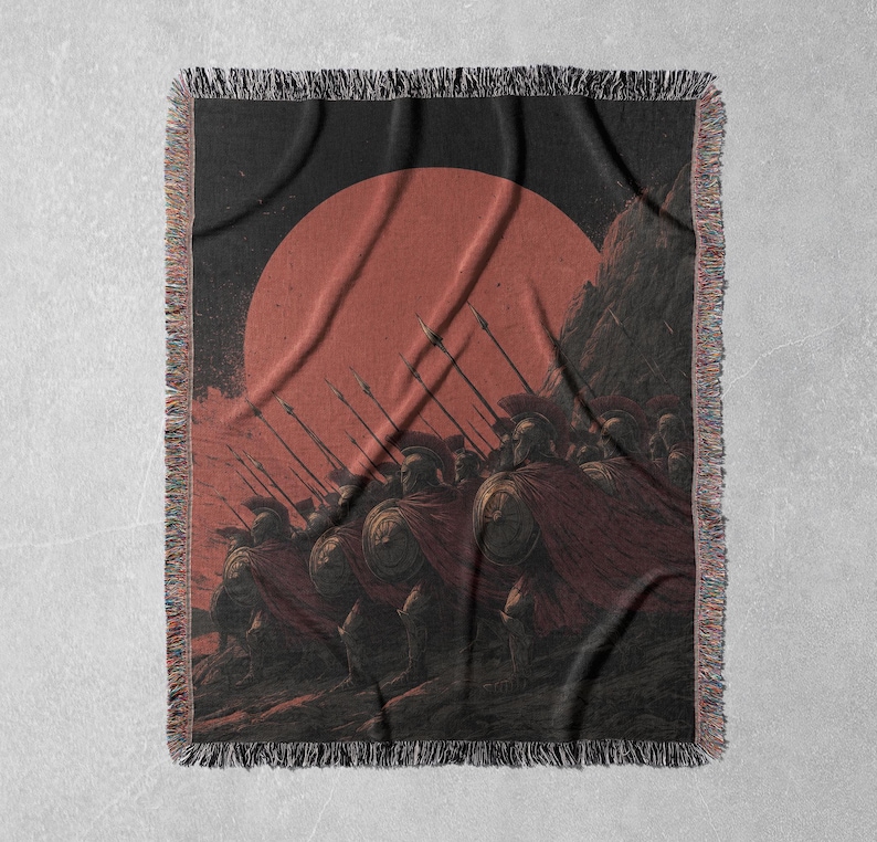 May include: Woven throw blanket featuring a historical illustration of a line of soldiers with spears, shields, and red capes, set against a red sun and dark background. The blanket has a fringed edge.