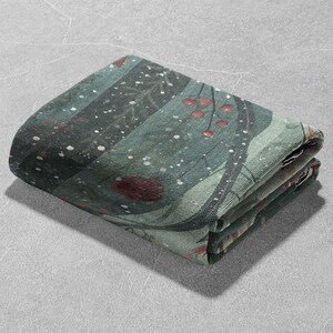 May include: Folded green and teal fabric with a nature-inspired design. The fabric features a pattern of branches, berries, and white speckles. The folded edges reveal the layers of the fabric.