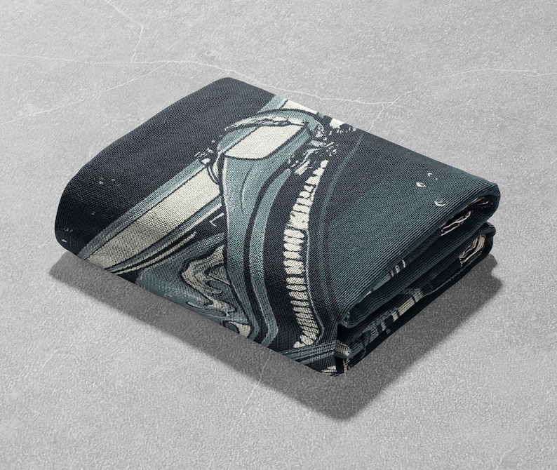 May include: A folded dark blue and white throw blanket with a graphic print of a spaceship. The blanket has a textured surface.