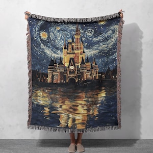 Può includere: Una coperta in tessuto a trama con un'illustrazione colorata del castello di Cenerentola su sfondo di cielo stellato. Il castello si riflette nell'acqua sottostante.