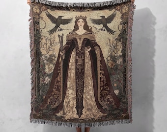 Puede incluir: Una manta de tejido de tapiz que presenta a una mujer con un vestido largo y fluido con una corona en la cabeza. Ella sostiene un bastón y está rodeada de pájaros y flores. El tapiz está en tonos marrones, dorados y verdes.