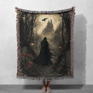 Puede incluir: Una manta de tiro de tapiz tejido que presenta una escena oscura y g&oacute;tica con una mujer con una capa negra caminando por un bosque hacia un castillo en la distancia. La escena se desarrolla con un fondo de &aacute;rboles, un cielo oscuro y un solo cuervo volando por encima. El tapiz est&aacute; enmarcado con un borde dorado y tiene flecos alrededor de los bordes.