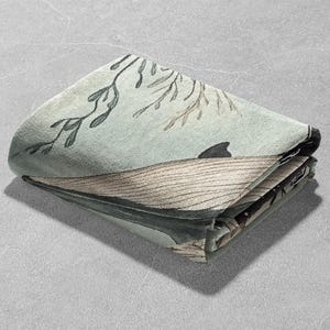 May include: A folded green and brown fabric with a whale and seaweed design. The fabric is folded in half and the edges are visible.