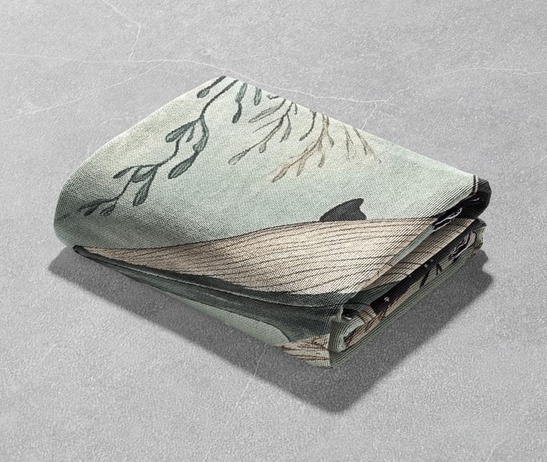 May include: A folded green and brown fabric with a whale and seaweed design. The fabric is folded in half and the edges are visible.