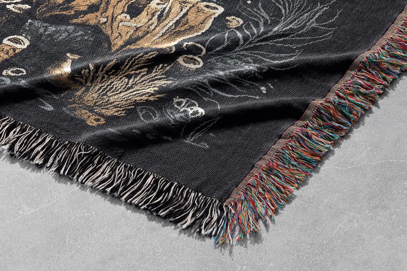 May include: Black and gold woven throw blanket with a fringed edge. The blanket features a floral design with a dark background.