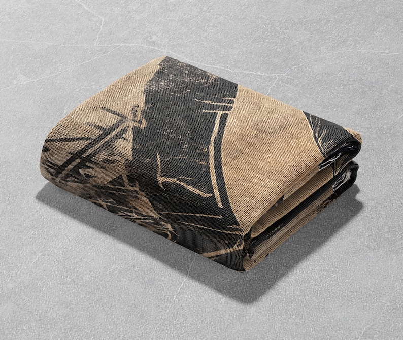 Pu&ograve; includere: Una coperta piegata di colore beige e nero con un design geometrico.